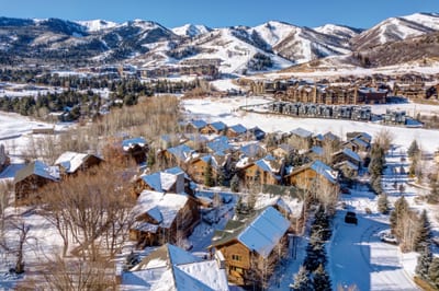 Snowy mountain village with cozy cabins nestled beneath ski resort slopes.