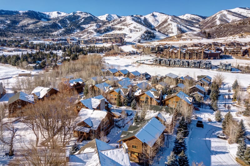 Snowy mountain village with cozy cabins nestled beneath ski resort slopes. TWL-5B