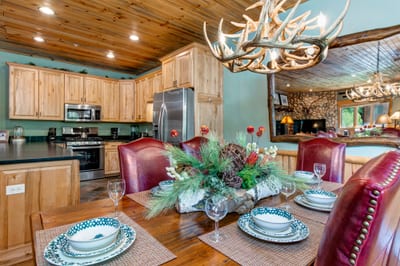 Dine at the large farmhouse-style table with seating for six under warm wood-paneled ceilings.