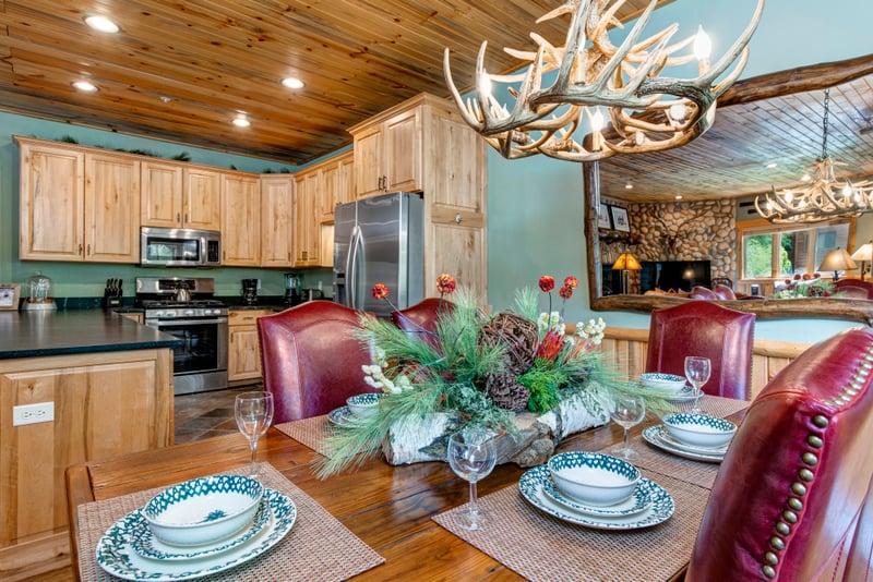 Dine at the large farmhouse-style table with seating for six under warm wood-paneled ceilings.