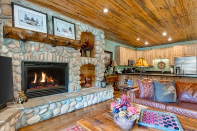 Gather in the living room with vaulted ceilings, a stone fireplace, and a Smart TV, perfect for relaxing after a day outdoors.