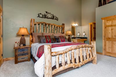 The primary bedroom offers a plush King bed, warm cabin styling, and ensuite bath access on the upper level.