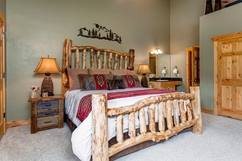 The primary bedroom offers a plush King bed, warm cabin styling, and ensuite bath access on the upper level.