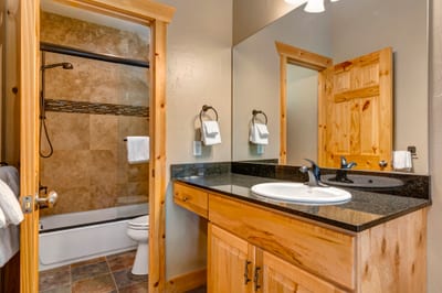 The guest bath includes dual granite vanities and a walk-in shower with stone tile.