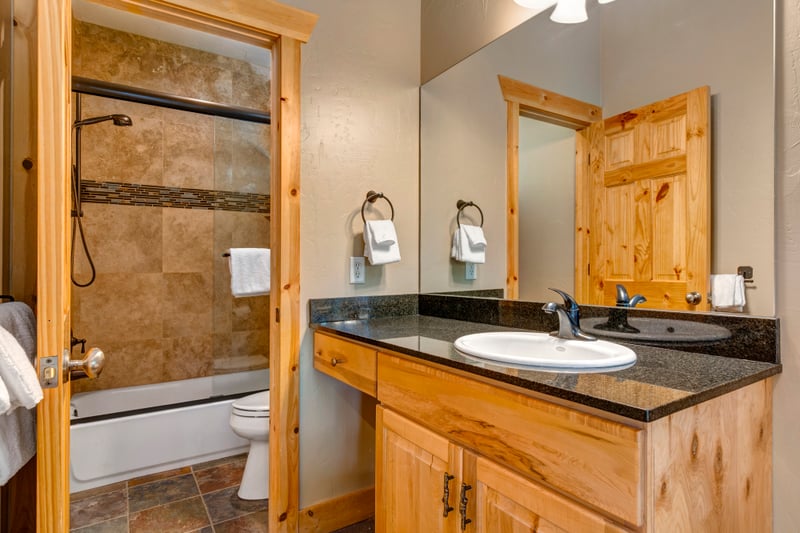 The guest bath includes dual granite vanities and a walk-in shower with stone tile.