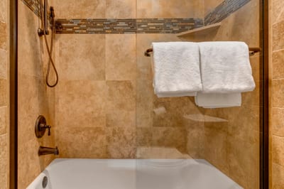 Refresh in the tiled shower-tub combo with bronze fixtures and built-in shelving for added convenience.