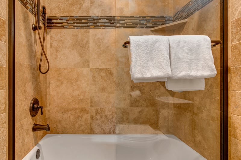 Refresh in the tiled shower-tub combo with bronze fixtures and built-in shelving for added convenience.