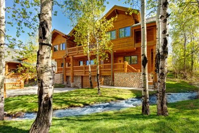 Tranquil cabin retreat: lush greenery, flowing stream, and rustic charm.