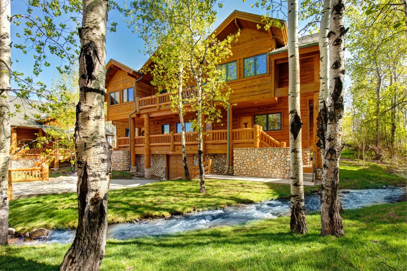 Tranquil cabin retreat: lush greenery, flowing stream, and rustic charm.