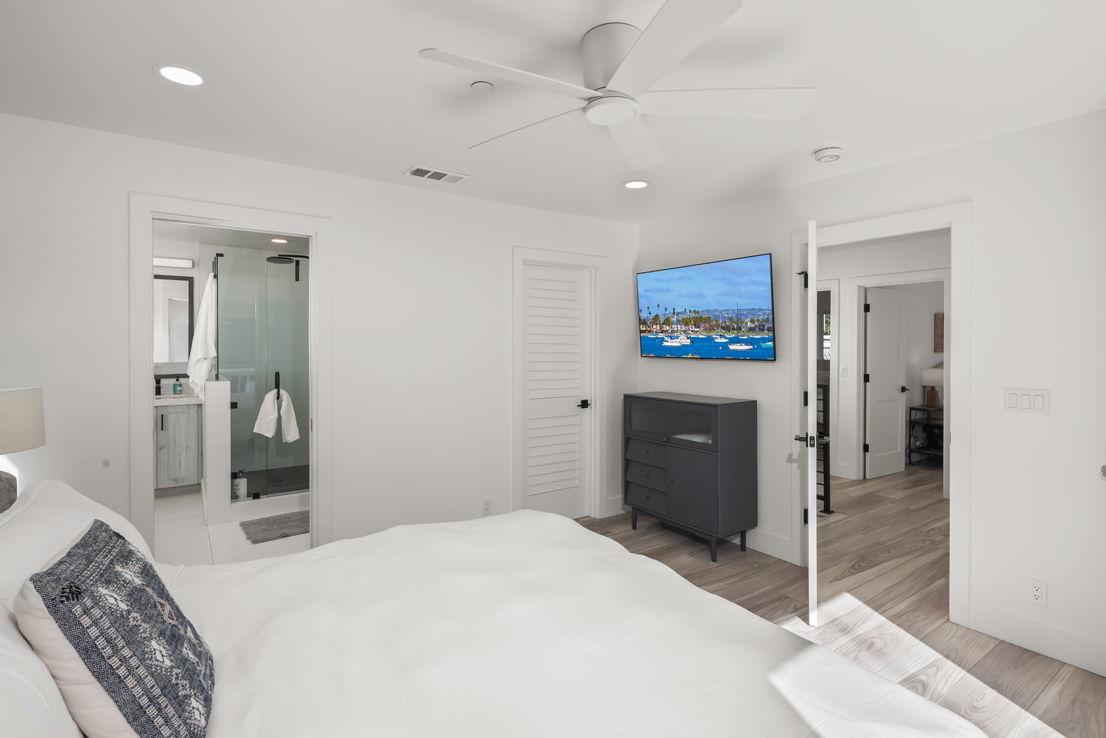 Stream a show from bed using the wall mounted TV, paired with a clean layout that keeps the space uncluttered.