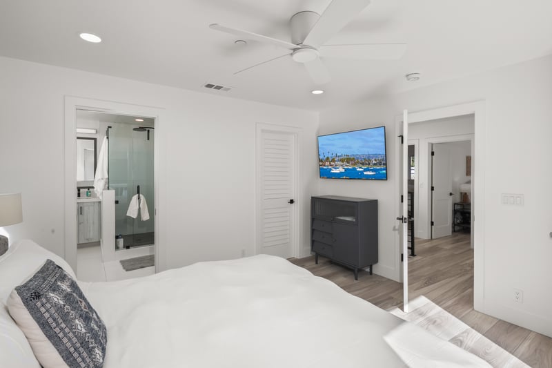 Stream a show from bed using the wall mounted TV, paired with a clean layout that keeps the space uncluttered.
