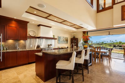 The kitchen features warm wood cabinetry, dark countertops, and a breakfast bar with seating