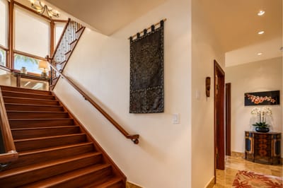Wide, natural wood stairs take you upstairs to the primary bedroom