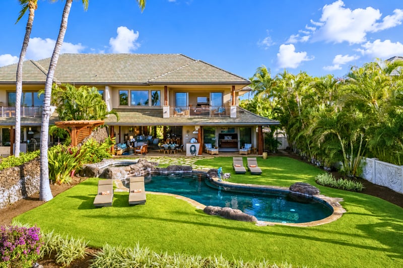 An aerial view captures the perfectly maintained lawn and pool area