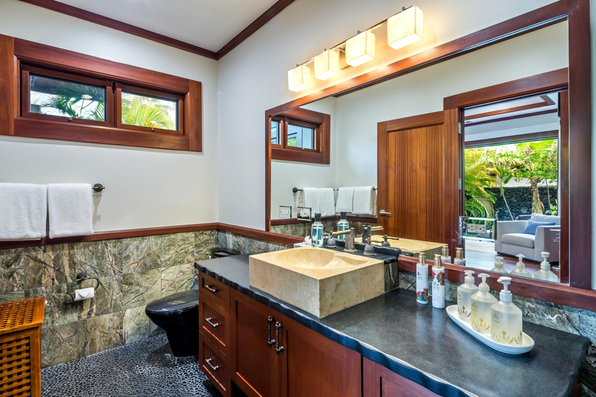 Guest bath includes granite counters, glass shower, and full L’Occitane amenities.