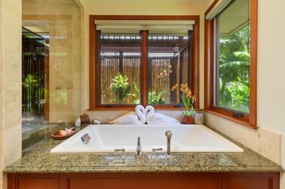 The soaking tub looks out onto lush, tropical foliage