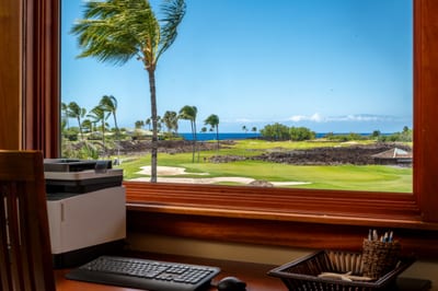 The desk area features expansive views of the golf course and a glimpse of the ocean beyond