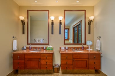 The primary bath features a dual vanity with stone counters and warm wood cabinetry