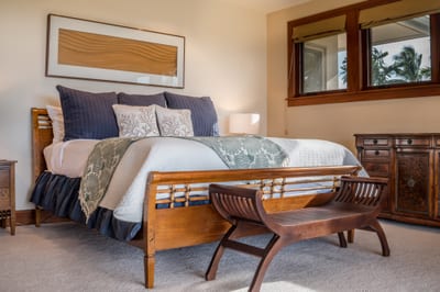 The primary bedroom features a king bed with ocean-inspired accents and warm wood tones
