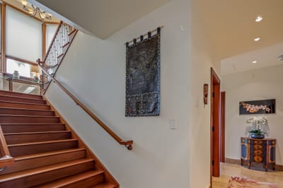 Wide, natural wood stairs take you upstairs to the primary bedroom