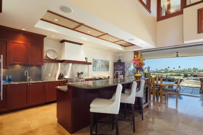 The kitchen features warm wood cabinetry, dark countertops, and a breakfast bar with seating
