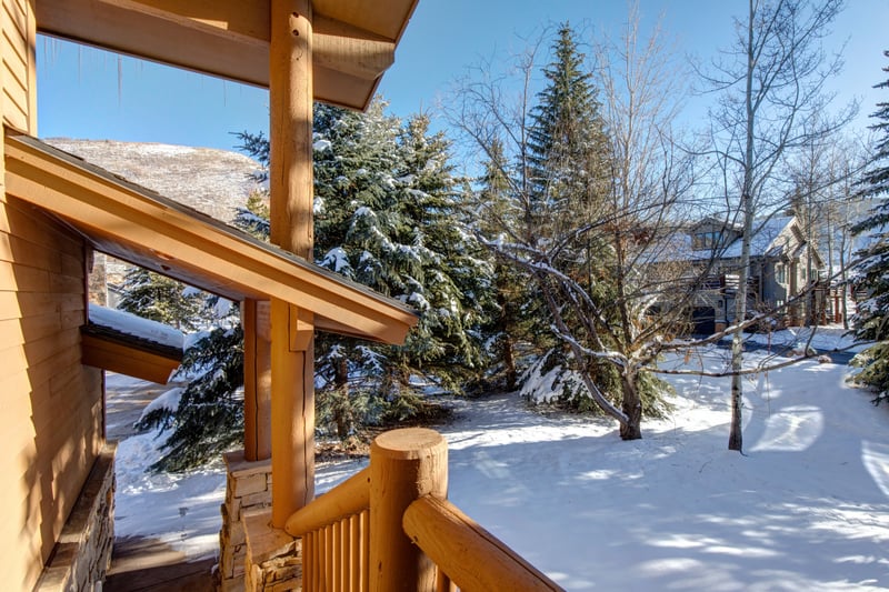 Snow-covered porch view — icicles and pine trees frame the surrounding Deer Valley mountainside