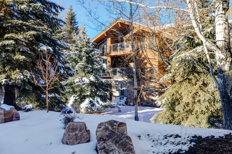 Exterior view of mountain lodge-style home nestled among snow-covered pines and aspens