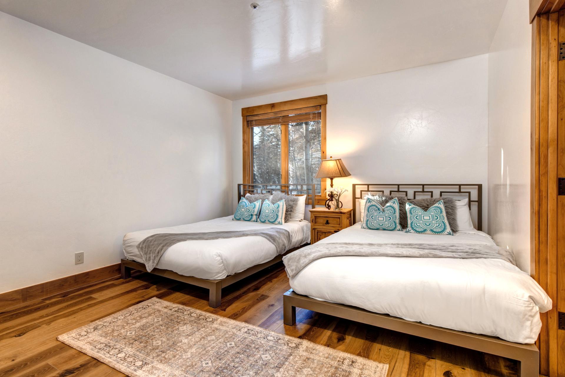 Two queen-size beds, warm wood floors, TV, and a private ensuite—perfect for comfort and convenience