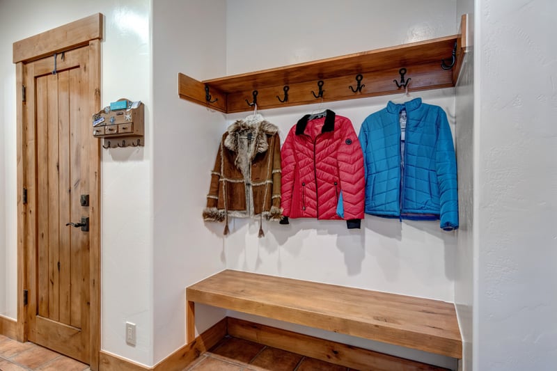 Mudroom entry with coat hooks and bench for storing ski jackets and gear steps from the front door