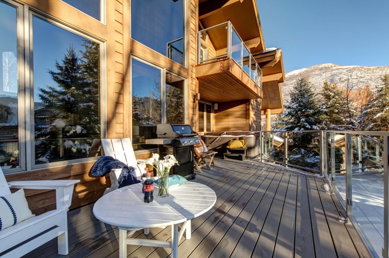 Outdoor deck, lounge seating, gas grill, and private hot tub with mountain backdrop