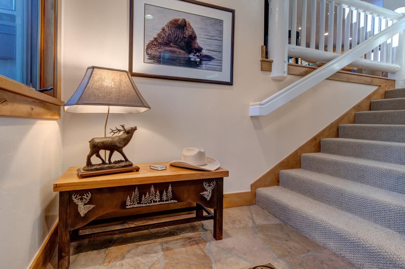Foyer carpeted staircase to the upper level with rustic lodge decor and wildlife art