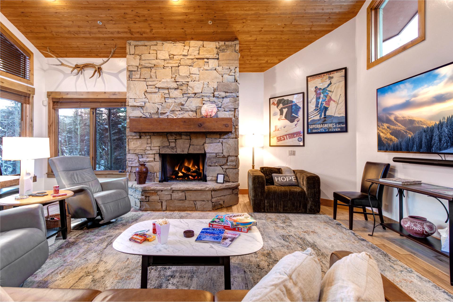 Gather in the inviting living room with a dramatic stone fireplace, vaulted wood ceilings, and comfortable seating for movie nights or fireside conversation.