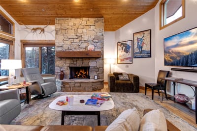 Gather in the inviting living room with a dramatic stone fireplace, vaulted wood ceilings, and comfortable seating for movie nights or fireside conversation.