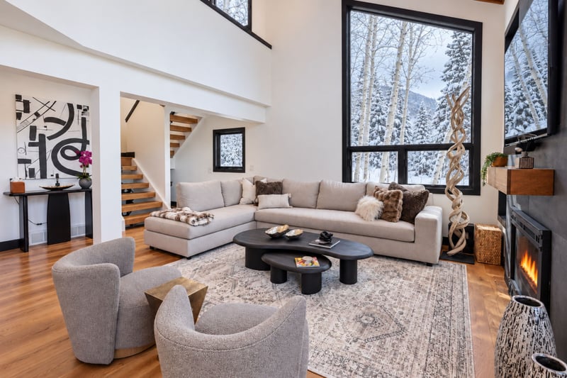 An elegant living room featuring soaring cathedral ceilings with exposed wood beams and captivating windows, the perfect space to gather and unwind.