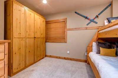 Cozy bedroom with bunk beds, wooden wardrobe, and carpeted flooring.