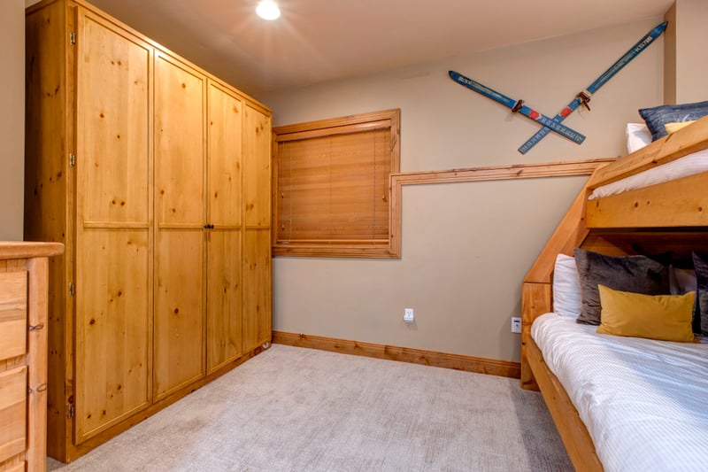 Cozy bedroom with bunk beds, Queen Murphy bed, wardrobe, and carpeted flooring.