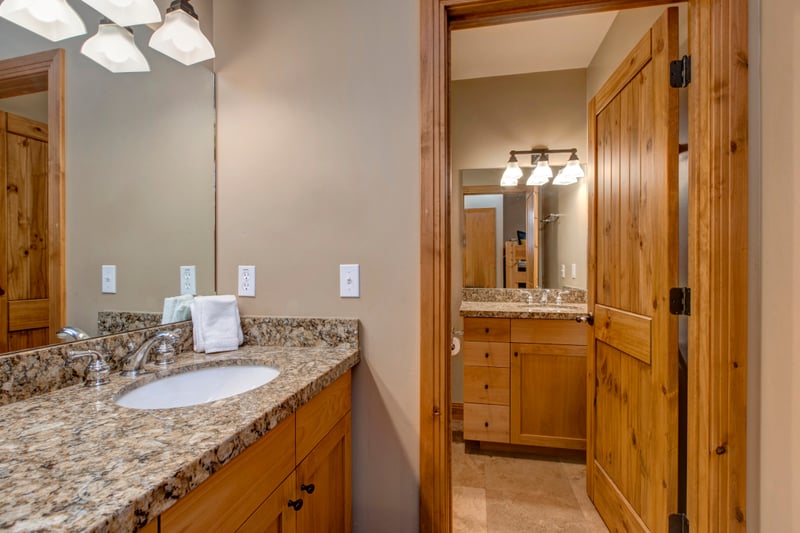 Elegant bathroom with granite countertop, wooden cabinets, and ample lighting.