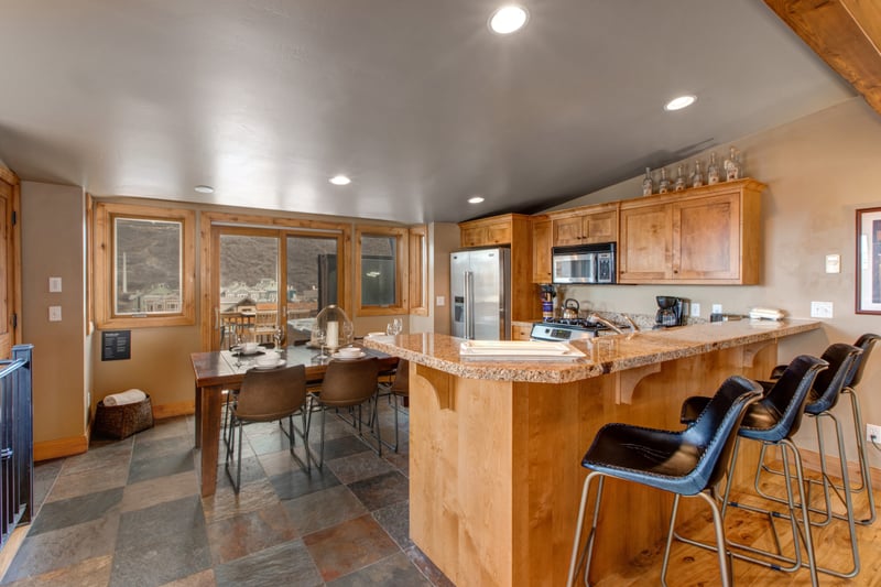 Bright kitchen and dining with granite countertops and mountain views outside.