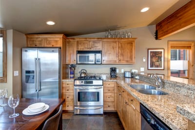 Modern kitchen with granite counters, stainless appliances, and wooden cabinetry.