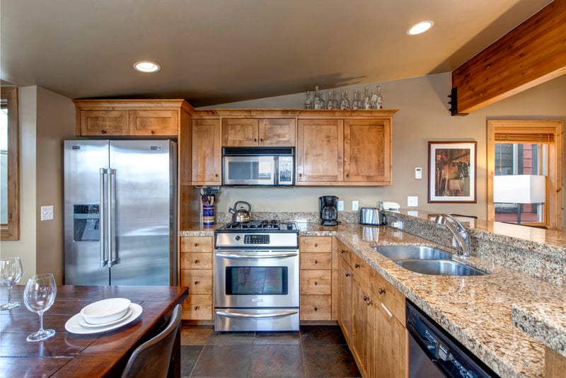 Modern kitchen with granite counters, stainless appliances, and wooden cabinetry.