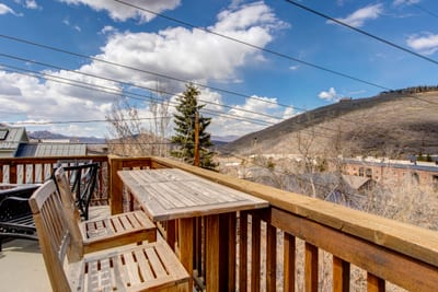 Cozy wooden balcony with mountain view under bright sunny skies.