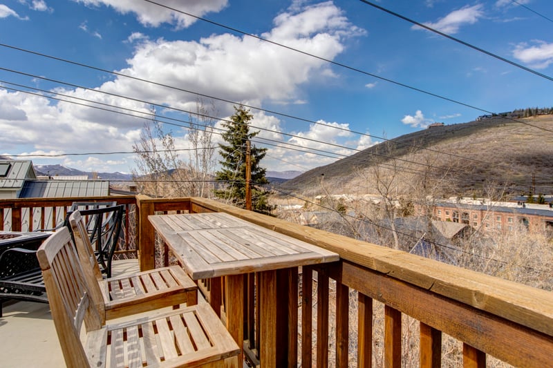 Cozy wooden balcony with mountain view under bright sunny skies.