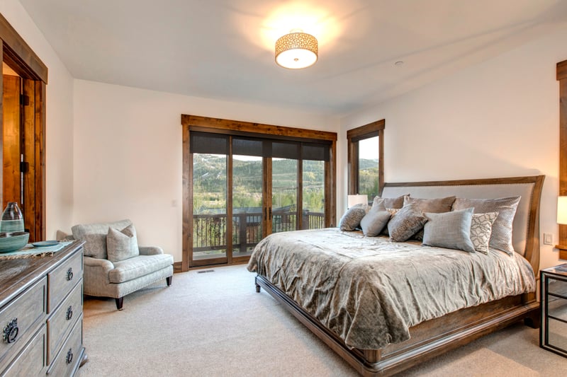 Guest Bedroom includes a plush King bed, cozy lounge chair, and private balcony access with panoramic mountain views.