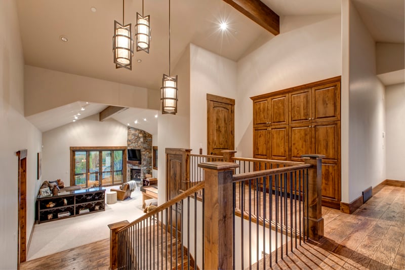 The upper landing features custom cabinetry, warm wood accents, and striking pendant lighting
