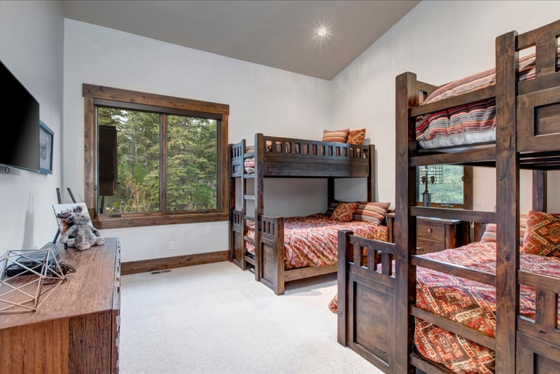 Spacious bunk room with tree views and cozy patterned bedding.
