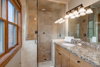 Elegant bathroom with granite countertop and glass-enclosed shower stall.