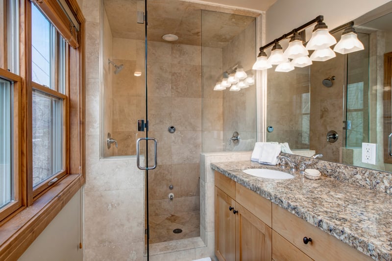 Elegant bathroom with granite countertop and glass-enclosed shower stall.