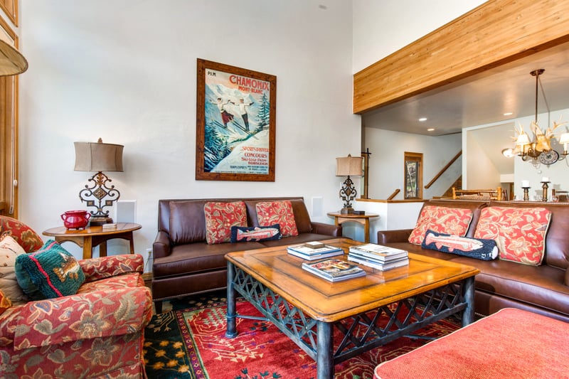 Relax in the main living room with leather seating, alpine décor, and vaulted ceilings open to the dining area.
