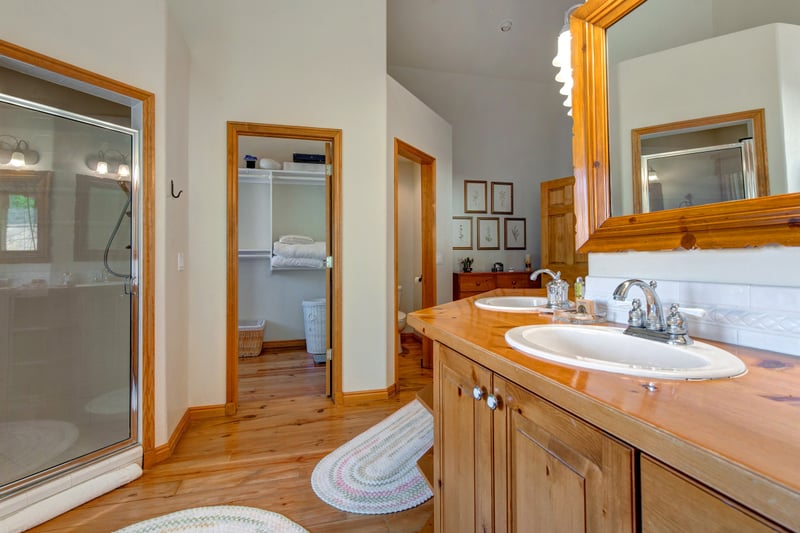 The primary ensuite combines natural stone, wood cabinetry, and spa-like features.
