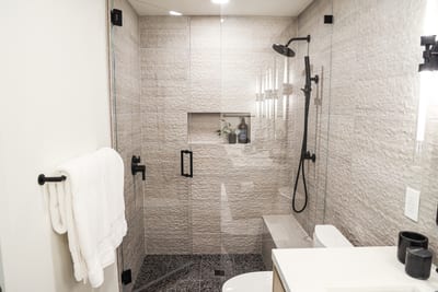 Black tile and a glass walk-in shower add a modern touch to the ensuite for Bedroom 6.